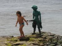 dit standbeeld van een vissend jongetje op ware grote herinnerd bezoekers aan de sterke link met de zee en dagelijks verdwijnt het beeld tijdens het opkomende tij.